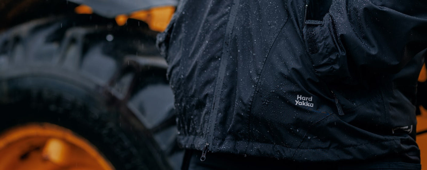 Close up image of a person wearing a Hard Yakka waterproof jacket in the rain