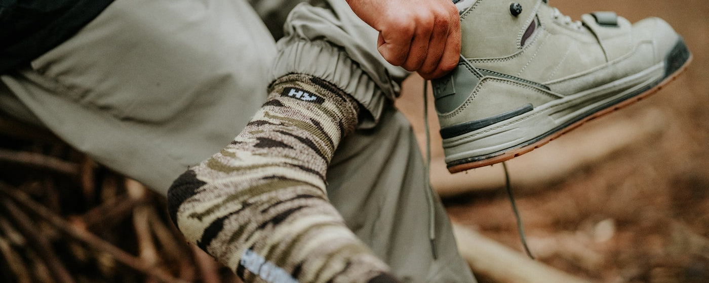 Close-up image of a man putting on an Olive Hard Yakka 3056 Safety Boot on a foot wearing a Hard Yakka Unisex Sock