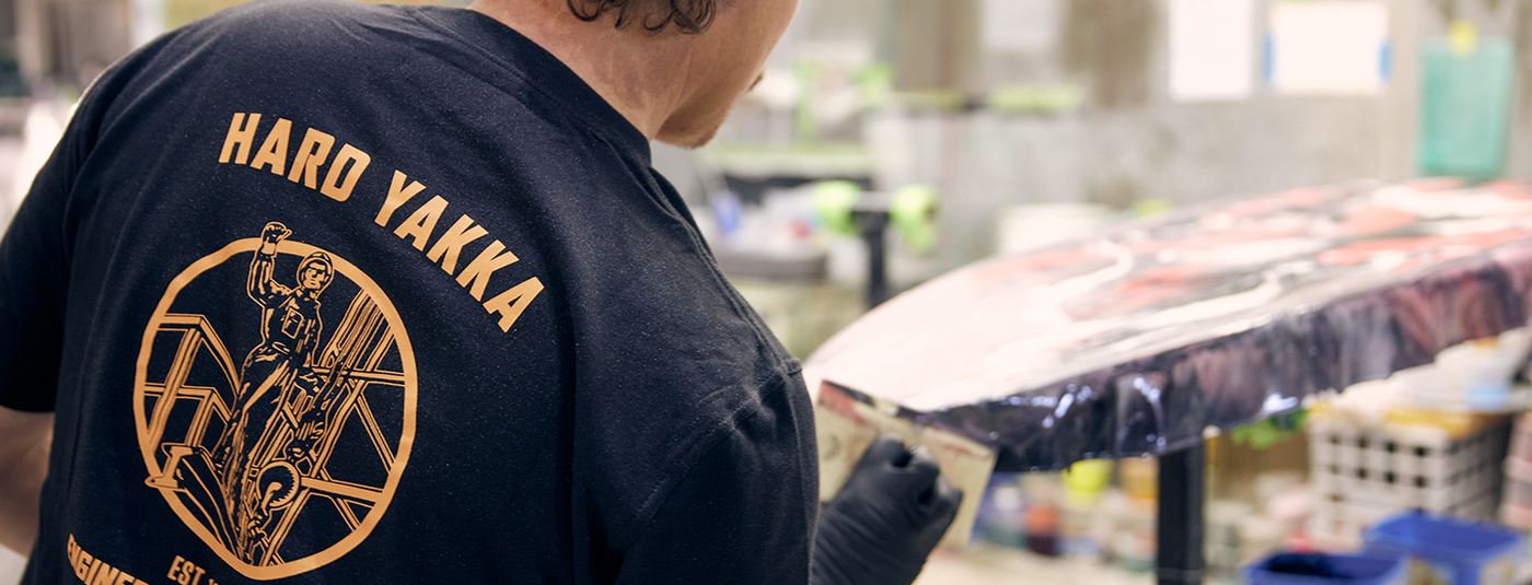 Man wearing a Hard Yakka T-Shirt Shaping a surfboard